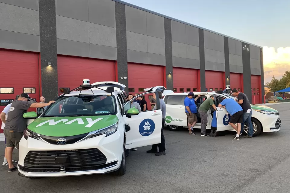 People examining parked goMARTI vans at launch event